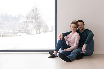 Image showing young couple sitting on the floor near window at home