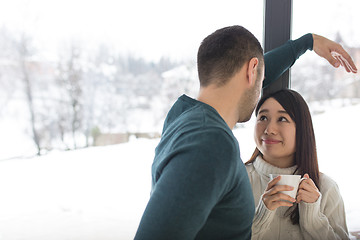 Image showing multiethnic couple enjoying morning coffee by the window