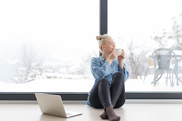 Image showing woman drinking coffee and using laptop at home