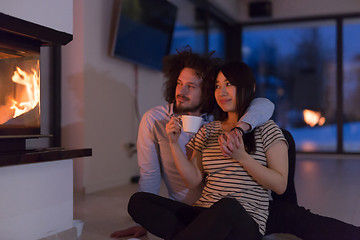 Image showing happy multiethnic couple sitting in front of fireplace