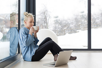 Image showing woman drinking coffee and using laptop at home