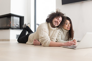 Image showing young multiethnic couple using a laptop on the floor