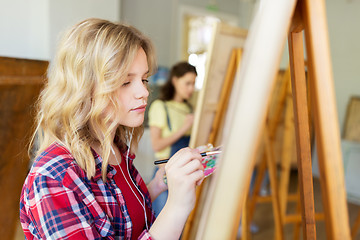 Image showing student girl with easel painting at art school