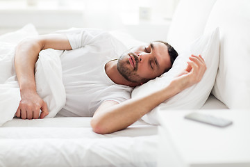 Image showing man sleeping in bed with smartphone on nightstand