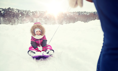 Image showing parent carrying happy little kid on sled in winter