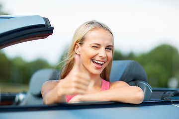 Image showing happy young woman in convertible car thumbs up