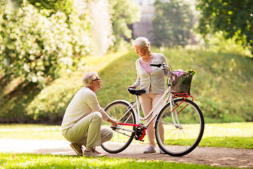 Image showing happy senior couple with bicycle at summer park