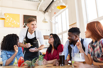 Image showing waiter and friends with menu and drinks at bar