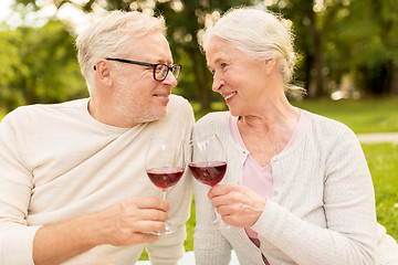 Image showing happy senior couple drinking wine at summer park