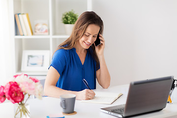 Image showing woman with notepad calling on smartphone at office