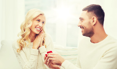 Image showing happy man giving engagement ring to woman at home