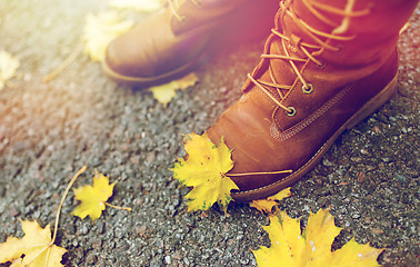 Image showing female feet in boots and autumn leaves