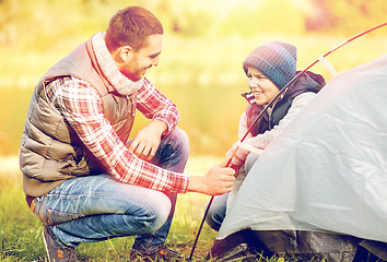 Image showing happy father and son setting up tent outdoors