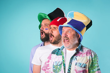 Image showing The three football fans singing the national anthem over blue