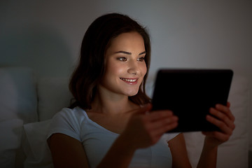 Image showing young woman with tablet pc in bed at home bedroom