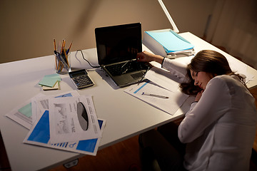 Image showing tired woman sleeping on office table at night