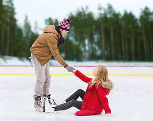 Image showing man helping woman to rise up on skating rink