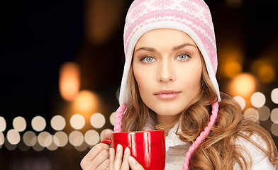 Image showing close up of woman with mug over christmas lights