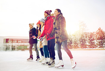 Image showing happy friends ice skating on rink outdoors