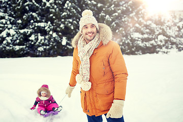 Image showing happy man carrying little kid on sled in winter