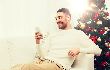 Image showing smiling man with smartphone at home for christmas