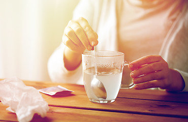 Image showing woman stirring medication in cup with spoon