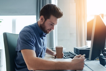 Image showing creative male office worker with coffee writing