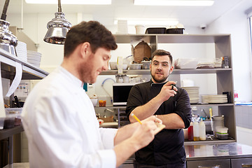 Image showing happy smiling chef and cook at restaurant kitchen