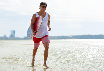 Image showing happy young man with skimboard on summer beach