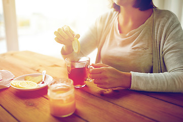 Image showing close up of woman adding lemon to tea cup