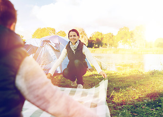 Image showing happy couple with picnic blanket at campsite