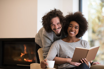 Image showing multiethnic couple hugging in front of fireplace