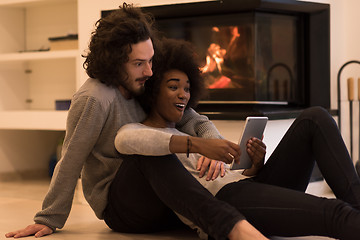 Image showing multiethnic couple using tablet computer on the floor