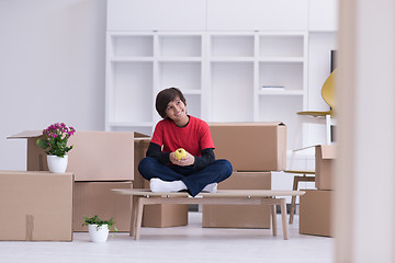 Image showing boy sitting on the table with cardboard boxes around him
