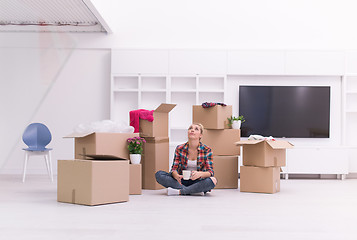 Image showing woman with many cardboard boxes sitting on floor