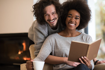 Image showing multiethnic couple hugging in front of fireplace