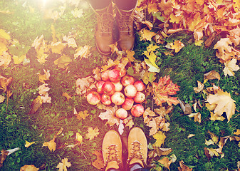 Image showing feet in boots with apples and autumn leaves