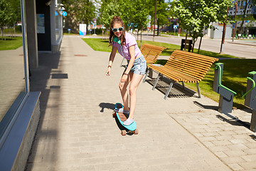 Image showing happy teenage girl in shades riding on longboard