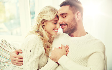 Image showing happy couple covered with plaid on sofa at home