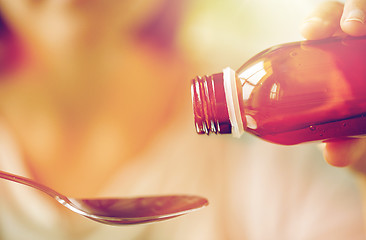 Image showing woman pouring medication from bottle to spoon