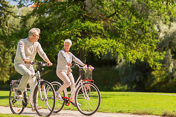 Image showing happy senior couple riding bicycles at summer park