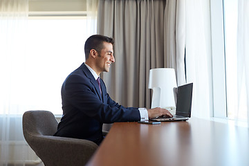 Image showing businessman typing on laptop at hotel room
