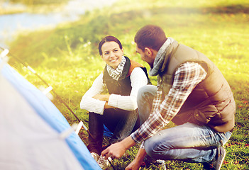 Image showing happy couple setting up tent outdoors