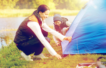 Image showing happy mother and son setting up tent outdoors