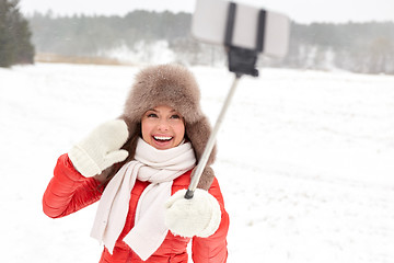 Image showing happy woman with selfie stick outdoors in winter