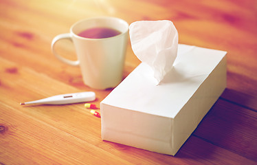 Image showing cup of tea, paper wipes and thermometer with pills