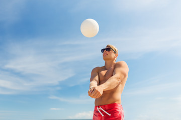 Image showing young man with ball playing volleyball on beach