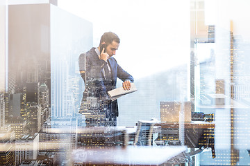 Image showing Businessman talking on mobile phone while looking at wristwatch.