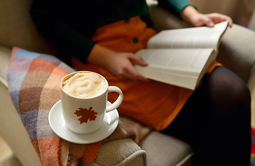 Image showing Cup of cappuccino and girl reading a book 