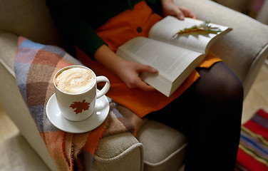 Image showing Cup of cappuccino and girl reading a book